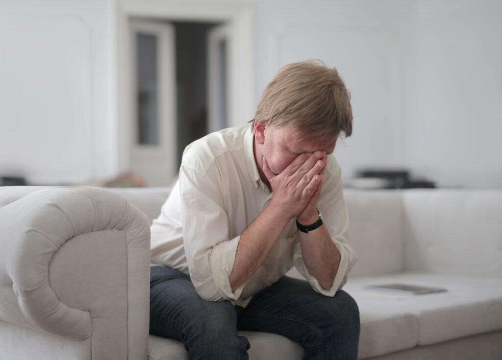 Mężczyzna przeżywa silne emocje, chowając twarz w dłoniach.